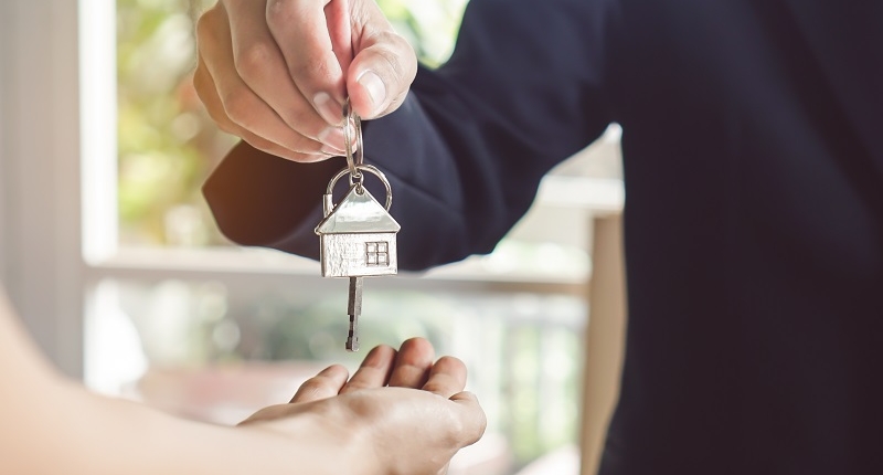 A Realtor Giving a Key from a House to a Buyer