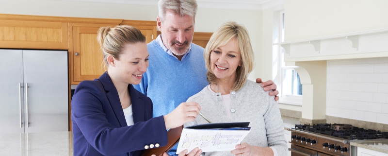 A Realtor Showing Mature Prospects a Property Brochure